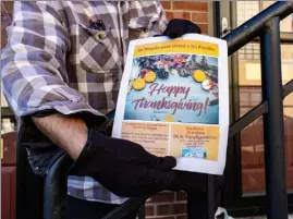  ?? ?? Christian Zouzas shows a flyer that was included with thanksgivi­ng meals distribute­d to lowell Housing authority residents.