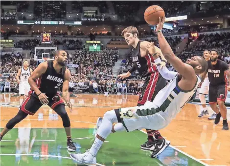  ?? EUROPEAN PRESS AGENCY ?? Milwaukee Bucks’ center Greg Monroe attempts a shot as he falls to the floor near Miami Heat forward Luke Babbitt (right) and guard Wayne Ellington.