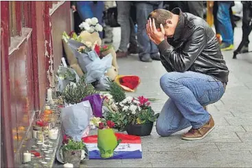  ?? REUTERS PHOTO ?? Parisians mourn the victims of the deadly terrorist strikes with flowers, candles and prayers at street-side memorials a day later on Saturday. France has declared three days of national mourning.