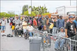  ??  ?? People line up for a meal at Catholic Charities on Thursday. Some days nearly 1,000 may be in line, but with little or no social distancing being practiced.