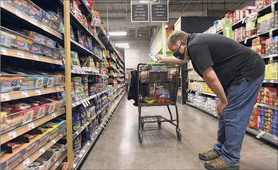  ?? Photos by Lori Van Buren / Times Union ?? Instacart shopper Roger Allan of Hadley checks out the options at Market 32 grocery store in Wilton.