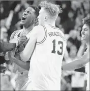  ?? Gregory Shamus Getty Images ?? CHARLES MATTHEWS, left, of Michigan celebrates his game-winning shot with teammates.