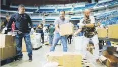  ??  ?? PONEN SU GRANITO. Joseph Fonseca y Oscar Serrano ayudan a organizar donativos en el Centro de Acopio del Coliseo de Puerto Rico.