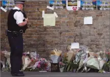  ?? The Associated Press ?? A police officer stands near floral tributes in Finsbury Park after an incident where a van struck pedestrian­s, in London on Monday.