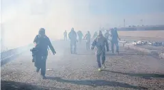  ?? AP ?? Migrants run from tear gas launched by US agents after a group of migrants were able to get past Mexican police at the Chaparral crossing in Tijuana on Sunday.