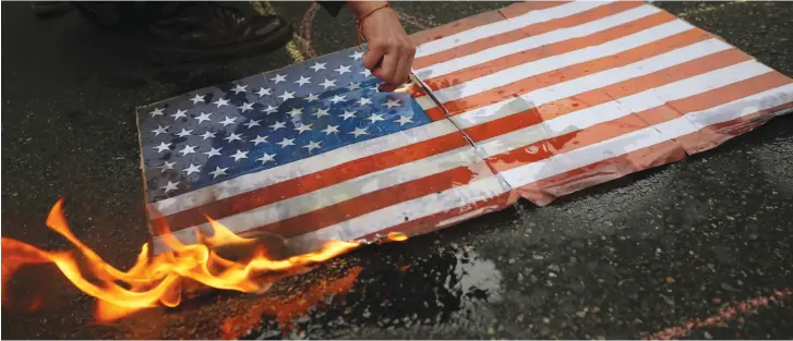  ?? (Reuters) ?? PROTESTERS BURN a US flag.