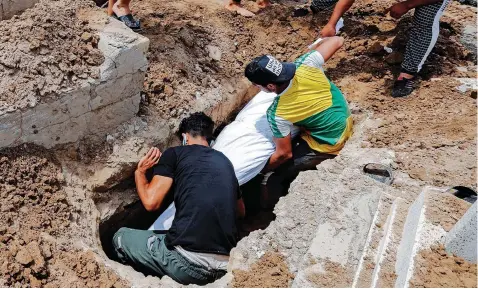  ?? | Reuters ?? MOURNERS bury the body of a man, who was killed in a fire at a hospital that had been equipped to house Covid-19 patients, at a cemetery in Baghdad, Iraq, yesterday.