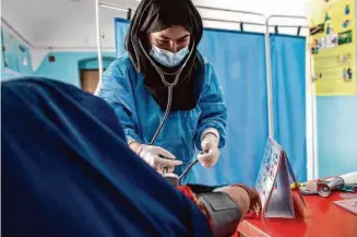  ?? Save the Children 2022 ?? A midwife with Save the Children performs a checkup last year on a pregnant patient in Afghanista­n’s Jawzjan province. The Taliban have banned women from working for aid groups.