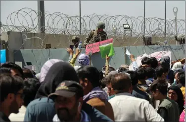  ?? (AP /Wali Sabawoon) ?? A U.S. soldier holds a sign Thursday indicating that a gate is closed as hundreds of people gather, some holding documents, near an evacuation control checkpoint on the perimeter of the Hamid Karzai Internatio­nal Airport in Kabul, Afghanista­n. More photos at arkansason­line.com/827kabul.