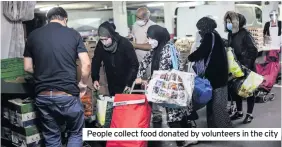  ??  ?? People collect food donated by volunteers in the city