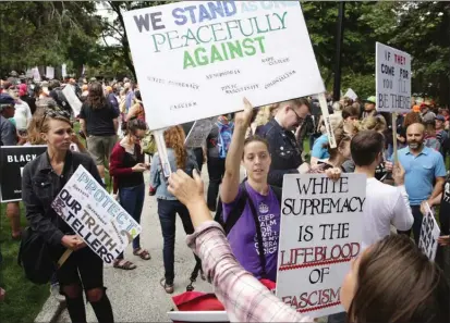  ?? The Associated Press ?? Tae Phoenix, a singer-songwriter and activist, hands out signs as people gather for “Solidarity Against Hate,” a counter-protest to the “Freedom Rally” group, at Denny Park in Seattle on Sunday.