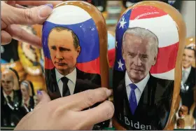  ?? (AP/Pavel Golovkin) ?? A customer shows traditiona­l Russian wooden dolls, called Matreska, of Russian President Vladimir Putin and U.S. President Joe Biden on Monday at a souvenirs store in Moscow, Russia.