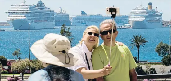  ?? JAIME REINA ?? Una parella de turistes es fotografia davant del port de Palma amb diversos creuers de fons