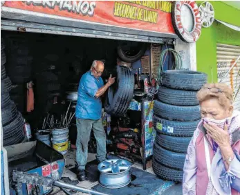  ?? FOTO: PEDRO PARDO/AFP ?? Eine Frau geht an einer Autowerkst­att in Mexiko-Stadt vorbei.