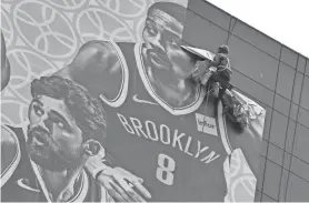  ?? HECTOR RETAMAL, AFP/GETTY IMAGES ?? A worker removes a promotiona­l banner from a building for an NBA preseason game in China between the Brooklyn Nets and the Los Angeles Lakers in Shanghai. Chinese state media slammed the NBA for an “about-face” on October 9 after the body said it would not apologise for a tweet by the Houston Rockets general manager supporting pro-democracy protests in Hong Kong.