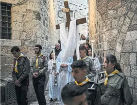  ?? ?? Above: A group of young Palestinia­n Arab scouts lead hundreds of Christians along the Way of the Cross, the route believed to have been walked by Jesus on his way to his crucifixio­n.