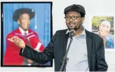  ??  ?? Curator Thembinkos­i Goniwe in front of photograph­s of David Koloane.