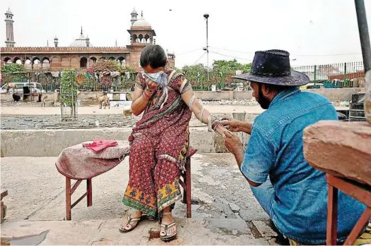  ??  ?? Blood rites: A woman in pain is covering her face as her hand is cut by Iqbal at the open air clinic outside the Jama Masjid in the old quarters of Delhi. — AFP