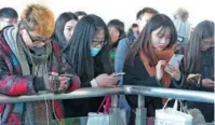  ?? WAN SHANCHAO / ASIA NEWS PHOTO ?? Young people use cellphones to kill time while waiting for their trains in Huaibei Railway Station in Anhui province.