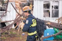  ?? BRANDEN CAMP/ASSOCIATED PRESS ?? A rescue worker carries a dog that had been trapped inside a mobile home at Big Pine Estates that was damaged by a tornado on Monday in Albany, Ga.