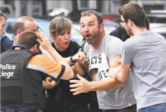  ?? Geert Vanden Wijngaert / Associated Press ?? Police try to calm a man who crossed over a police line at the scene of a shooting in Liege, Belgium. The gunman, who was later killed by police, was on a two-day leave from prison.