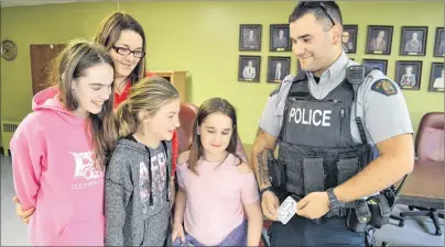  ?? ERIC MCCARTHY/JOURNAL PIONEER ?? Cst. J-P Cote shows Suzanne Getson and children, from left, Ella Gavin, Amiyah Getson and Mary Jane Gavin Shea the Narcan kit containing naloxone that officers carry in case they are exposed to the drug, fentanyl. During an informatio­n session on how to talk to children about drugs, Cote said only a small amount of fentanyl, equivalent to a few grains of sand, can be lethal.