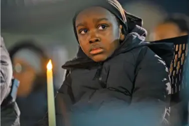  ?? KAITLIN NEWMAN /THE BALTIMORE BANNER VIA AP ?? A young boy holds a candle as he listens to victims’ names read aloud Wednesday during a vigil for the homicide victims of 2023 in Baltimore.