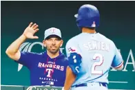  ?? Associated Press ?? ■ Texas Rangers manager Chris Woodward, left, congratula­tes Marcus Semien (2) after Semien hit a solo home run during third inning of a baseball game Sunday against the Seattle Mariners in Arlington, Texas.