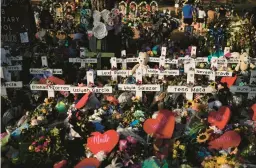  ?? JAE C. HONG/AP ?? Flowers are piled around crosses with the names of the victims in a school shooting as people visit a memorial May 31, 2022, at Robb Elementary School in Uvalde, Texas.