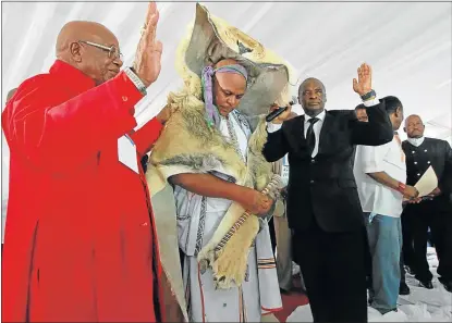  ?? Picture: LULAMILE FENI ?? ANOINTED: AmaMpondo King Zanozuko Tyelovuyo Sigcau, centre, wears a lion’s skin after being enrobed by Chief Apostle Dr Caesar Nongqunga, right, in the black suit, with the assistance of Bishop Joseph Sigqibo Kobo, left. ● See more pictures on page 8