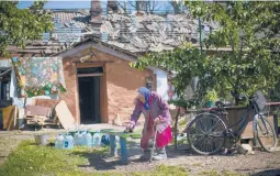  ?? FRANCISCO SECO/AP ?? A resident of the eastern Ukrainian town of Pokrovsk removes dust from a bench outside her heavily damaged house on Wednesday after two Russian rocket strikes.