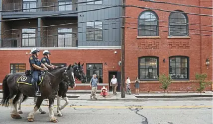  ?? Steve Mellon/Post-Gazette ?? Two members of the Pittsburgh Police mounted patrol make their way down West North Avenue last Thursday shortly before the grand opening of Allegheny City Stables Lofts on Pittsburgh’s North Side. From left are Justin Susich on Lord Stanley and Walt Jones on Spirit.