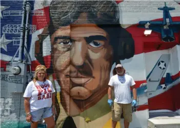 ?? (Special to The Commercial/Richard Ledbetter) ?? Candace McCollum (left) and mural artist Jason White stand in front of the newly completed portrait of Vice Admiral Jimmy Thach, Fordyce native and inventor of the flight maneuver the “Thach Weave.”