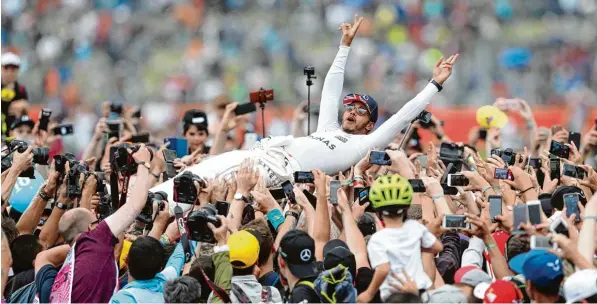  ?? Foto: David Davies, dpa ?? Nach seinem Triumph in Silverston­e wirft sich Sieger Lewis Hamilton wie ein Rockstar in die Menge und genießt seinen Erfolg.