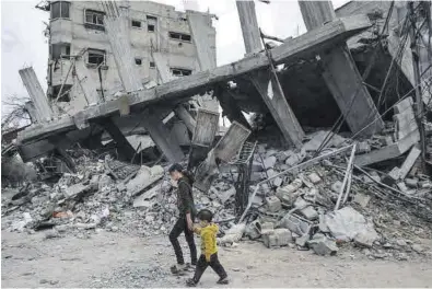  ?? MOHAMMED SABER / EFE ?? Dos niños pasan, junto a un edificio destruido por el Ejército israelí en el campo de refugiados de Al Bureije, en Gaza.