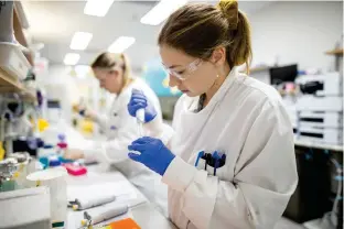  ??  ?? Eve Radunz (right, foreground) and Mallory Daleris run analytics on the vaccine. Radunz (below) prepares equipment for the vaccine’s purificati­on.