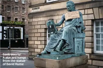  ??  ?? Controvers­y: A placard hangs from the statue of David Hume