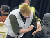  ?? ?? A woman administer­s a Moderna booster vaccine Dec. 27 to a woman in Antwerp, Belgium.