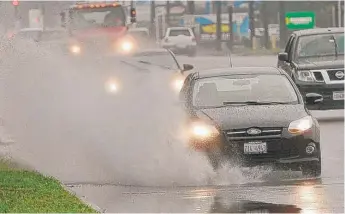  ?? | BOB CHWEDYK/ DAILY HERALD PHOTO ?? Cars splash through rain puddles along Busse Road in Mount Prospect Saturday.