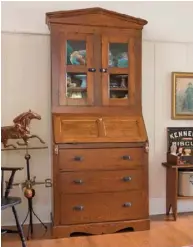  ??  ?? Far left: The placement of a tall antique secretary desk echoes the slope of the living room ceiling, creating a pleasing focal point. Its glass doors safely contain fragile majolica dishware while keeping it on view. The arrangemen­ts flanking the secretary are quite different, but they are equally weighted for visual appeal.