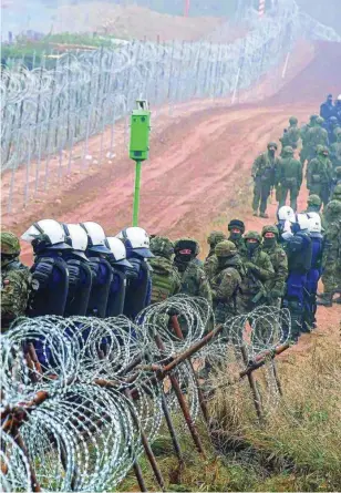  ?? REUTERS ?? Soldados polacos en la valla fronteriza de Kuznica