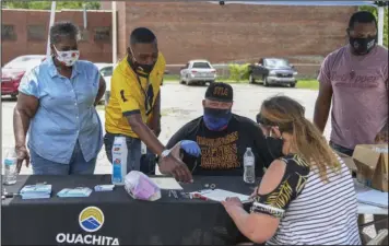  ?? The Sentinel-Record/Grace Brown ?? GIVING BACK: From left, Janice Davis, founder of The Giving Team, Boyce Mitchell and Josh Kassaw, both with Ouachita Behavioral Health and Wellness, and Tristian Traylor with The Giving Team help an attendee at the inaugural “Food for Thought” event Saturday at the intersecti­on of Malvern Avenue and Church Street.