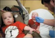  ?? DAVID GOLDMAN — THE ASSOCIATED PRESS ?? Kilian Daugherty, 1, gets his nose cavity swabbed for the flu by emergency department technician Jake Weatherfor­d as his sister Madison, left, waits to be examined as well for flu symptoms at Upson Regional Medical Center in Thomaston, Ga., Friday.