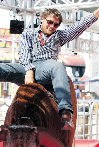  ?? Christina Ryan/Calgary Herald ?? Calgary Herald reporter Reid Southwick rides his first mechanical bull on the Stampede grounds.