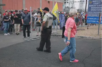  ?? WASHINGTON POST ?? An election worker walks past pro-Trump protesters alleging voter fraud at the Maricopa County vote-counting centre in Phoenix, Arizona in 2020. Election officials are prepared for more disruption from conspiracy theorists during this year’s presidenti­al election.