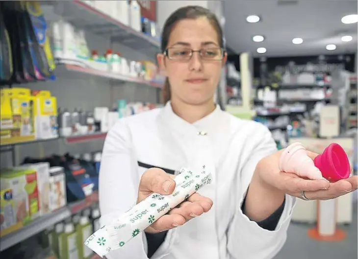  ??  ?? La dependient­a de una farmacia de Lesseps muestra tampones cien por cien de algodón natural y las copas menstruale­s que se venden en su establecim­iento