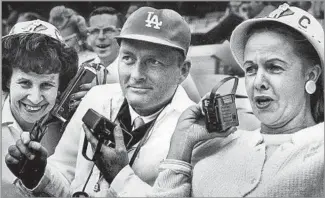  ?? Cal Montney Los Angeles Times ?? FROM LEFT, 1965 Dodgers booster club members Gladys Fuqua, Rolfe Larsen and Vangie Scoler listen to Vin Scully broadcast from St. Louis while they attend an Angels game at Dodger Stadium.