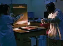  ?? Lisa Krantz / Staff photograph­er ?? Researcher­s at UTSA pull a sample of lunar basalt simulant out of a furnace to melt and quench it to glass.