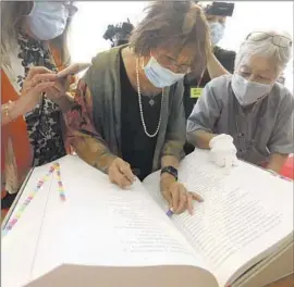  ?? Genaro Molina Los Angeles Times ?? JUNE AOCHI Berk, center, marks her father’s and mother’s names in the sacred book during Saturday’s ceremony at the Japanese American National Museum.