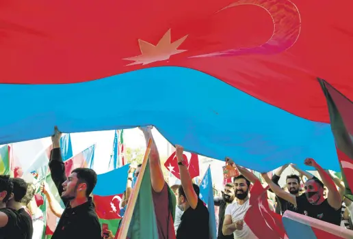  ??  ?? Protesters wave a huge Azerbaijan­i flag in demonstrat­ions against Armenia in Istanbul, Turkey, Oct. 4, 2020.